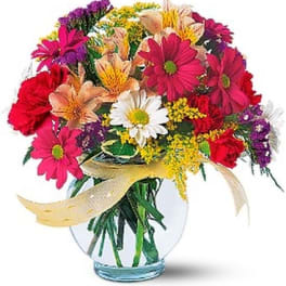 Colorful mixed bouquet in a clear glass vase with a ribbon