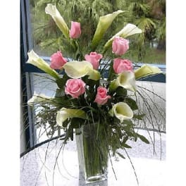 Pink roses and white calla lilies in a tall glass vase