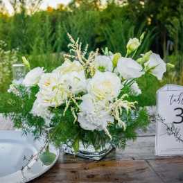White floral centerpiece in a clear glass vase on a table