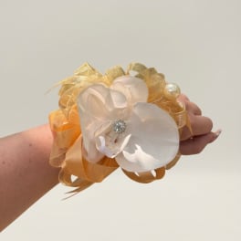 White orchid wrist corsage with gold ribbon and pearl accent