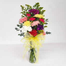 Colorful carnation bouquet in a glass vase with a yellow ribbon