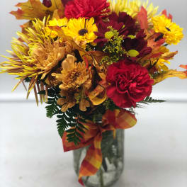 Autumn bouquet of red, yellow, and orange flowers in a glass vase