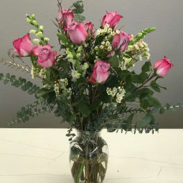 Pink roses in a clear glass vase with white filler flowers