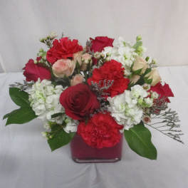 Red and white mixed flower arrangement in a square glass vase