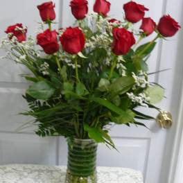 Red roses arranged in a clear glass vase with white filler flowers