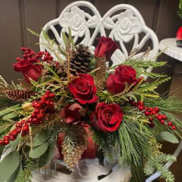 Red roses arranged with pinecones and berries in a white chair