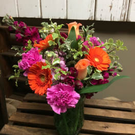 Bright mixed bouquet in a glass vase with orange gerberas and pink carnations