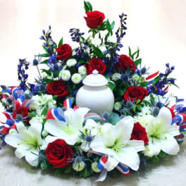 Red roses and white lilies arranged around a white urn