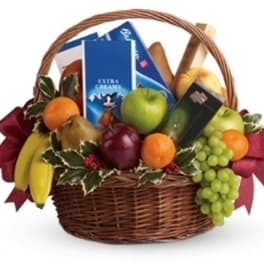Fruit basket with apples, bananas, grapes, and packaged snacks in a wicker basket