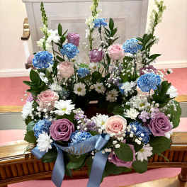 Floral wreath with pink and purple roses, blue carnations, and white daisies
