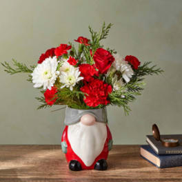 Red and white flowers in a Santa-shaped ceramic container