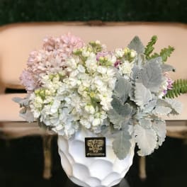 White and pale pink flowers in a white vase with silver foliage
