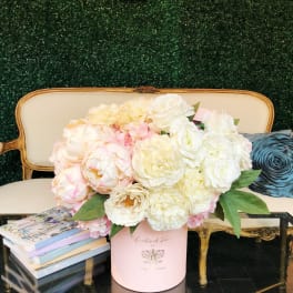 Pink and white flower arrangement in a round box on a table