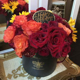 Bouquet of red, coral, and yellow flowers in a black hat box