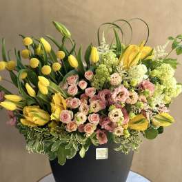 Yellow tulips and pink roses arranged in a black vase