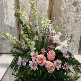 Pink roses and white flowers arranged around a glass cross