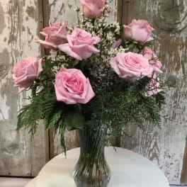 Pink roses arranged in a clear glass vase with white filler flowers