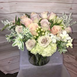 Pastel rose bouquet in a glass vase with white filler flowers