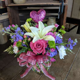 Bouquet of pink roses, white lilies, and purple flowers with a glitter heart pick