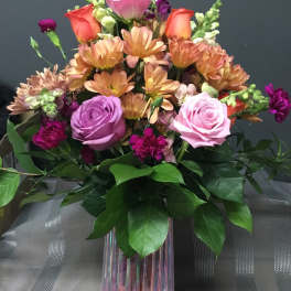 Mixed bouquet of roses, chrysanthemums, and snapdragons in a glass vase