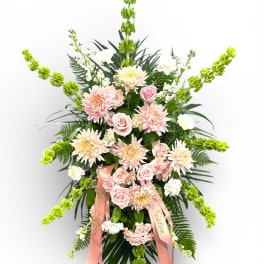 Standing floral spray with pink roses, pale chrysanthemums, and green spikes