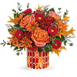 Orange and red floral arrangement in a patterned vase