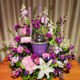 Purple and pink floral arrangement around a purple urn