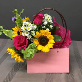 Pink gift bag with sunflowers, roses, and white daisies