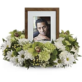 White and green floral frame around a photo in a wooden frame
