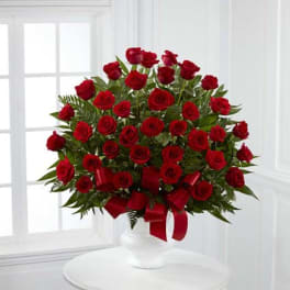 Red rose arrangement in a white vase with a red ribbon