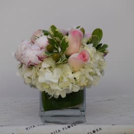 Pink and white floral arrangement in a square glass vase