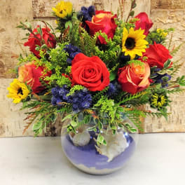 Mixed bouquet of red roses and yellow sunflowers in a round glass vase