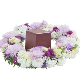 Lavender and white floral wreath surrounding a brown cremation urn box