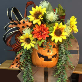 Pumpkin-shaped container with sunflowers and orange flowers