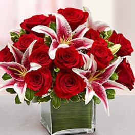 Red roses and pink lilies arranged in a square glass vase