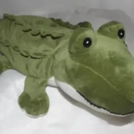 Green plush alligator toy lying on white fabric