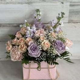 Pastel rose bouquet in a pink box with gold chain handles