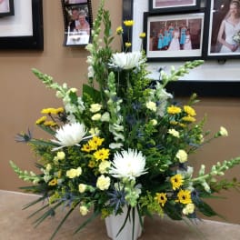 Tall mixed floral arrangement in a white vase with white and yellow blooms