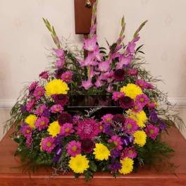 Large funeral spray with pink gladiolus and yellow and purple mums