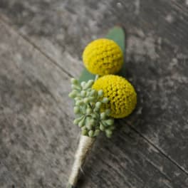 Small boutonniere with two yellow pom-pom flowers and pale green buds