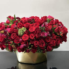 Dense red rose arrangement in a gold vase