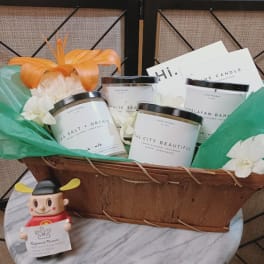 Gift basket with candles, white flowers, and a small figurine