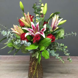 Bouquet of red roses and pink lilies in a glass vase