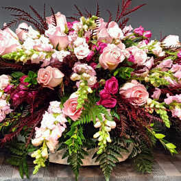 Large pink rose arrangement with burgundy foliage and white accent flowers