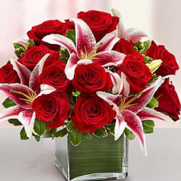 Red roses and pink lilies arranged in a square glass vase