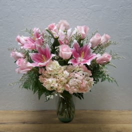 Pink lilies and roses arranged in a glass vase
