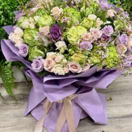 Lavender and green bouquet of roses wrapped in purple paper