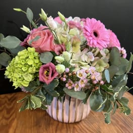 Pink and green mixed flower arrangement in a striped vase