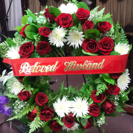 Red rose and white daisy funeral wreath with a red ribbon