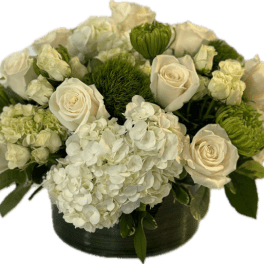 Low arrangement of white roses and hydrangeas with green accent flowers in a dark round vase